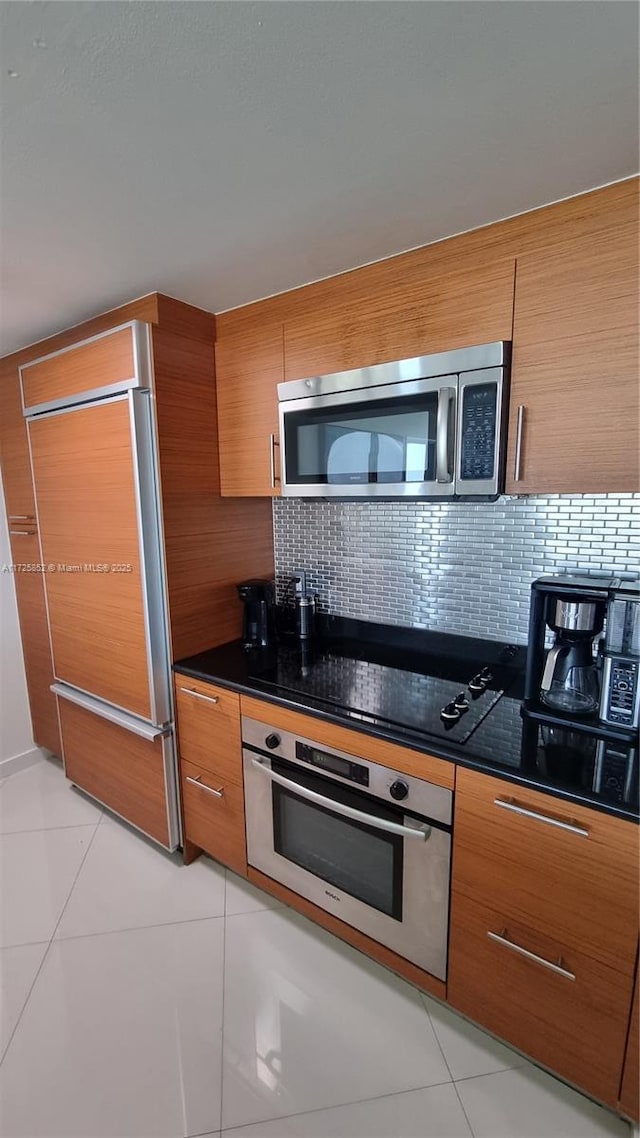 50 Biscayne Blvd Unit 1902, Miami, FL 33132 - kitchen with stainless steel appliances, brown cabinetry, dark countertops, and tasteful backsplash