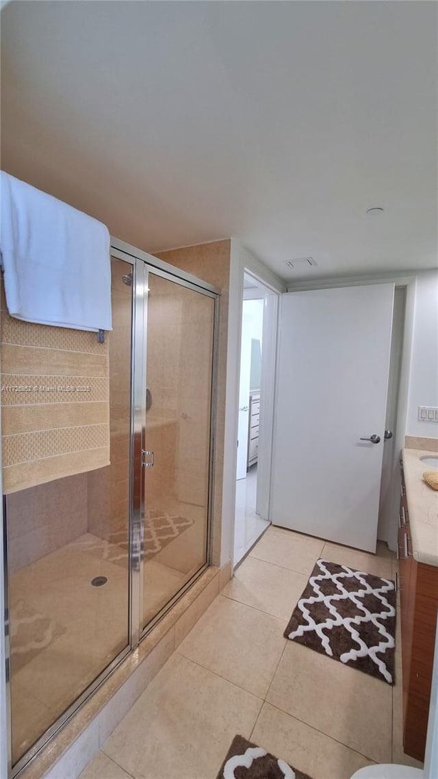 bathroom with walk in shower, vanity, and tile patterned floors