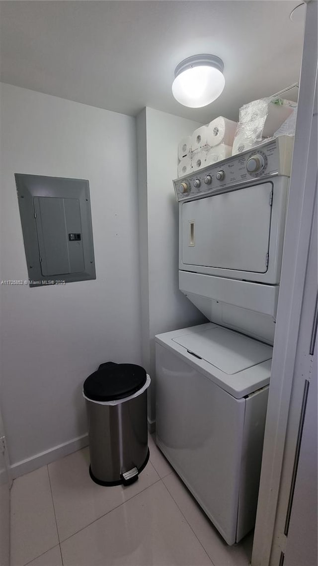 laundry area featuring light tile patterned floors, electric panel, and stacked washer / drying machine