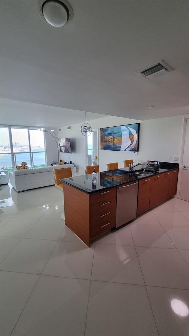 kitchen with stainless steel dishwasher, light tile patterned floors, sink, and pendant lighting