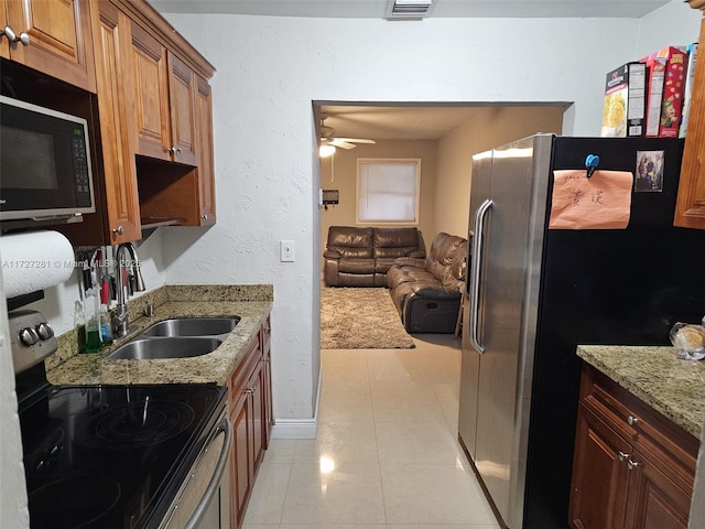 kitchen featuring light stone countertops, appliances with stainless steel finishes, sink, light tile patterned flooring, and ceiling fan