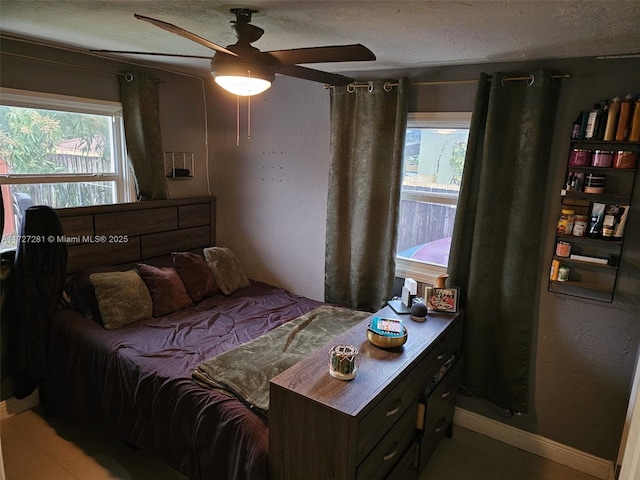 bedroom featuring ceiling fan, a textured ceiling, and multiple windows