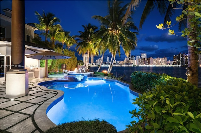 view of pool featuring exterior kitchen, an in ground hot tub, exterior bar, a water view, and a patio