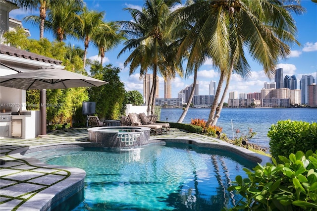 view of pool featuring an outdoor kitchen, a water view, pool water feature, and an in ground hot tub