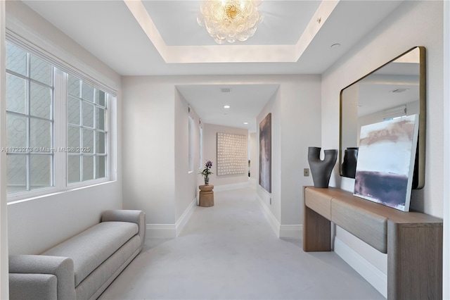 corridor featuring a chandelier and a raised ceiling