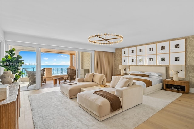 bedroom featuring access to outside, light hardwood / wood-style floors, and a water view