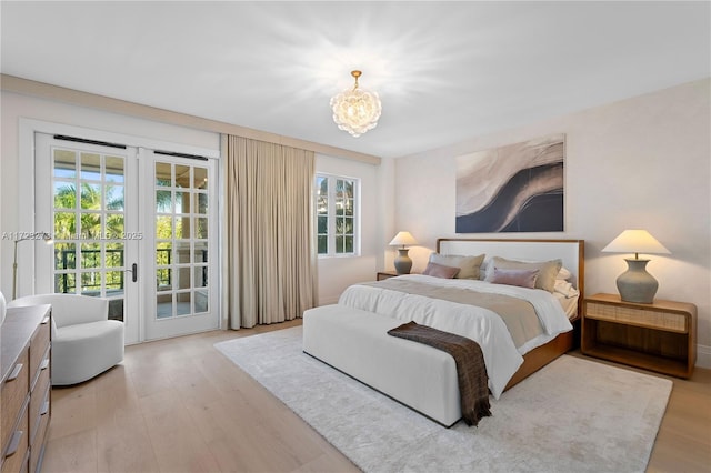 bedroom featuring an inviting chandelier, access to exterior, light hardwood / wood-style flooring, and french doors