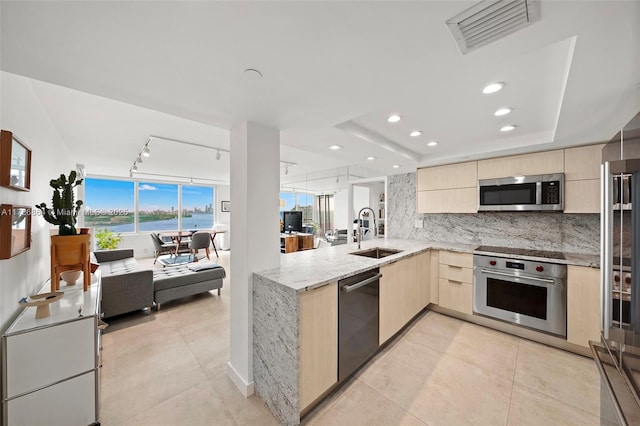 kitchen featuring kitchen peninsula, stainless steel appliances, light brown cabinets, track lighting, and sink