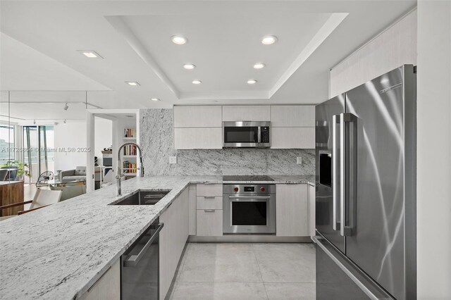 kitchen featuring sink, light brown cabinets, a raised ceiling, and stainless steel appliances