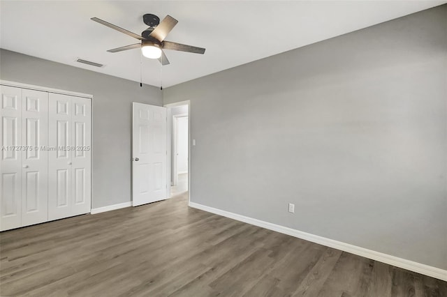 unfurnished bedroom featuring ceiling fan, a closet, and dark wood-type flooring