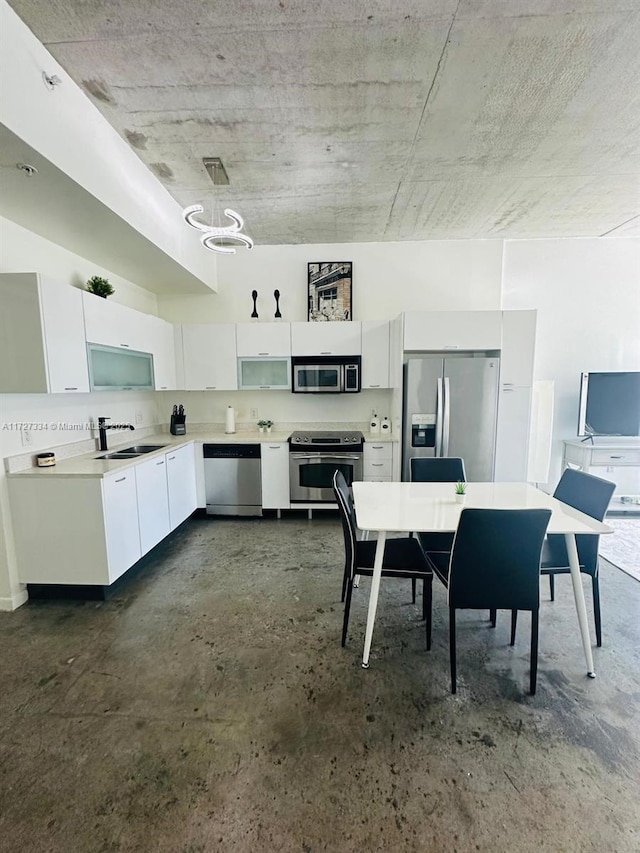 kitchen featuring decorative light fixtures, white cabinets, appliances with stainless steel finishes, and sink