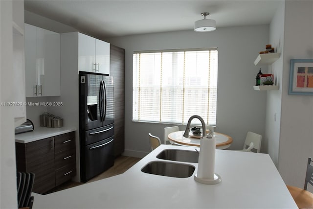 kitchen with dark brown cabinets, plenty of natural light, black fridge with ice dispenser, and white cabinetry