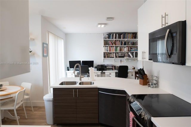 kitchen with white cabinets, dark brown cabinetry, dishwasher, sink, and range with electric cooktop