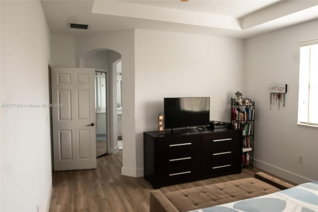 bedroom featuring wood-type flooring and a tray ceiling