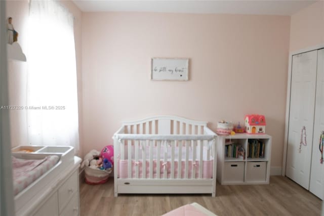 bedroom featuring a crib and light hardwood / wood-style floors