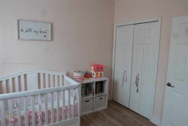 bedroom featuring light wood-type flooring, a closet, and a nursery area