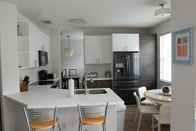 kitchen featuring black appliances, decorative light fixtures, a kitchen bar, white cabinetry, and kitchen peninsula