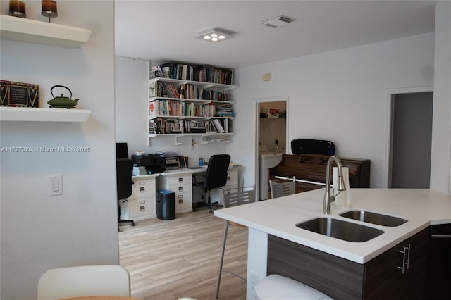 kitchen featuring dark brown cabinets, light hardwood / wood-style flooring, washer / clothes dryer, and sink