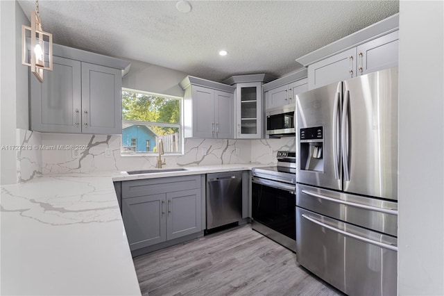 kitchen featuring gray cabinets, stainless steel appliances, tasteful backsplash, and sink