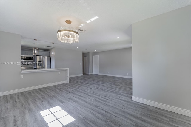 unfurnished living room featuring wood-type flooring, a notable chandelier, and a textured ceiling