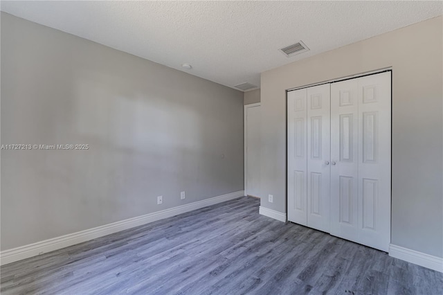 unfurnished bedroom with a closet, a textured ceiling, and hardwood / wood-style flooring