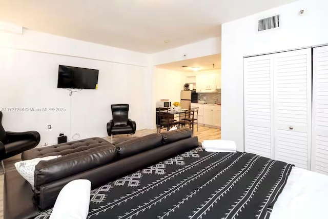 bedroom with ensuite bath, a closet, and stainless steel refrigerator