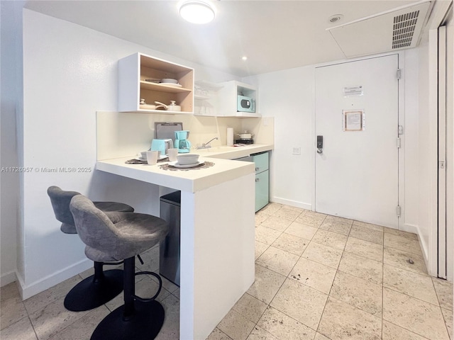 kitchen with white cabinets, kitchen peninsula, a kitchen breakfast bar, and sink