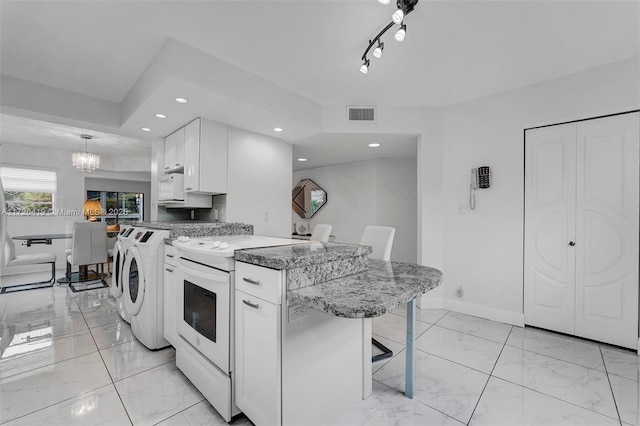 kitchen with white appliances, a kitchen breakfast bar, independent washer and dryer, pendant lighting, and white cabinets