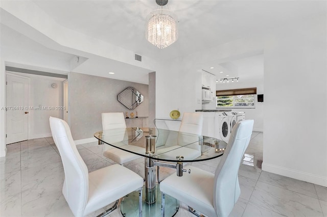 dining space featuring washer and dryer and a chandelier