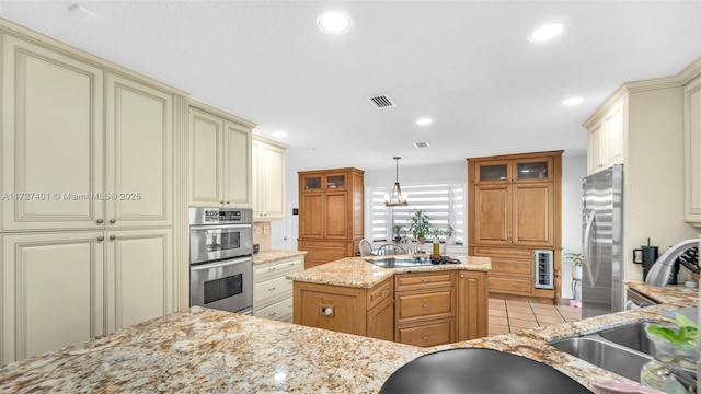 kitchen featuring light tile patterned floors, stainless steel appliances, hanging light fixtures, light stone counters, and a center island