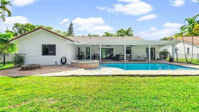 rear view of house featuring a pool with hot tub, an outdoor fire pit, ceiling fan, a patio area, and a yard