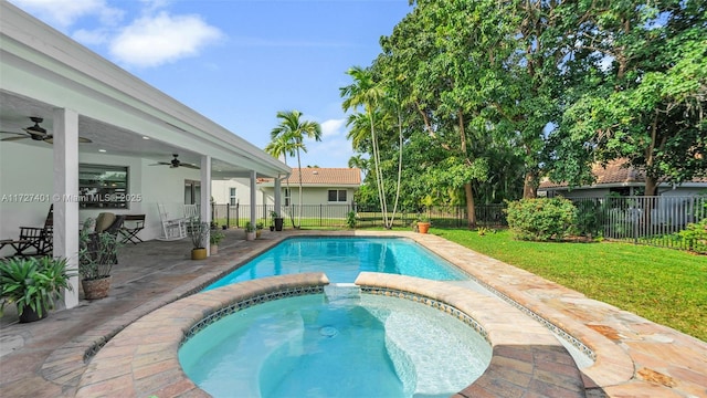 view of swimming pool with ceiling fan, a patio, a yard, and an in ground hot tub