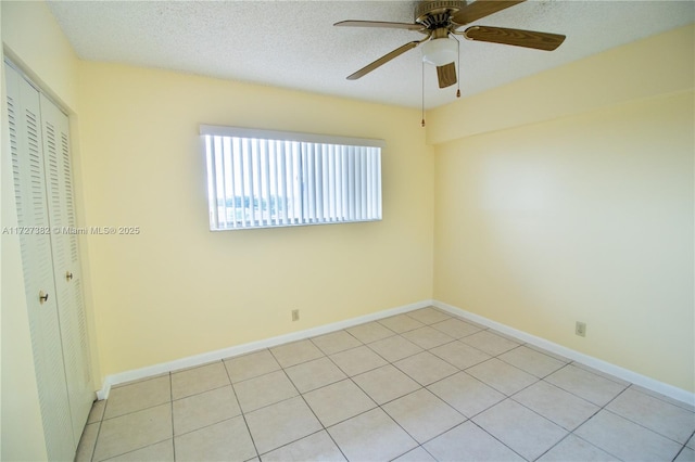 unfurnished room with ceiling fan, light tile patterned floors, and a textured ceiling