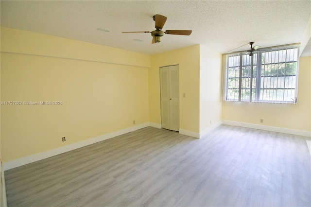 empty room with ceiling fan, wood-type flooring, and a textured ceiling