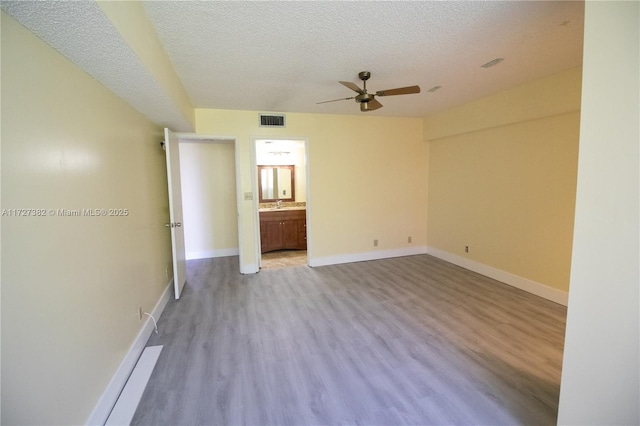 empty room with ceiling fan, sink, a textured ceiling, and light hardwood / wood-style flooring