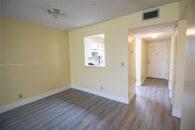 unfurnished room with a textured ceiling, hardwood / wood-style flooring, and sink