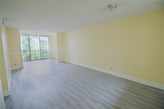 empty room featuring expansive windows, a textured ceiling, and light hardwood / wood-style flooring