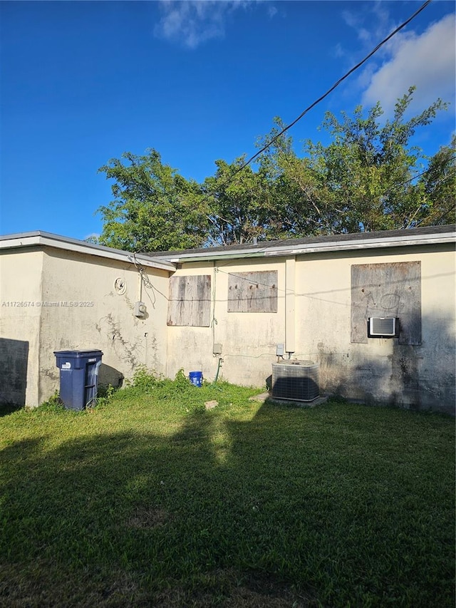 back of property with a yard and central AC unit