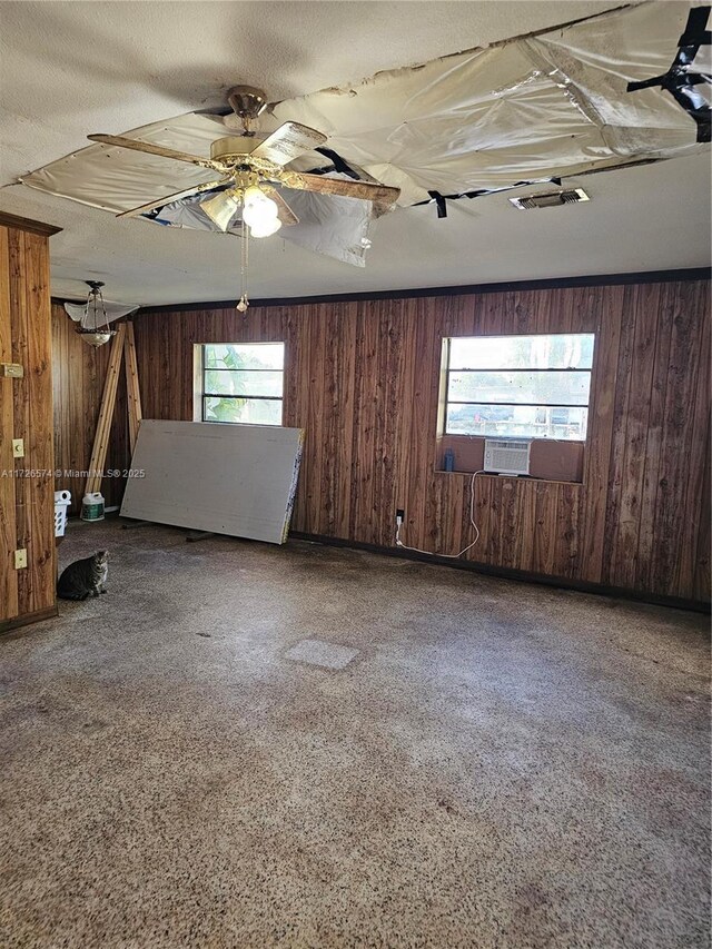 empty room featuring ceiling fan and wooden walls