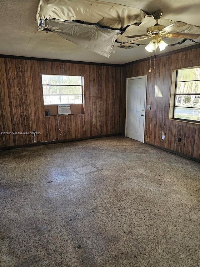 carpeted spare room featuring crown molding, a textured ceiling, and wood walls