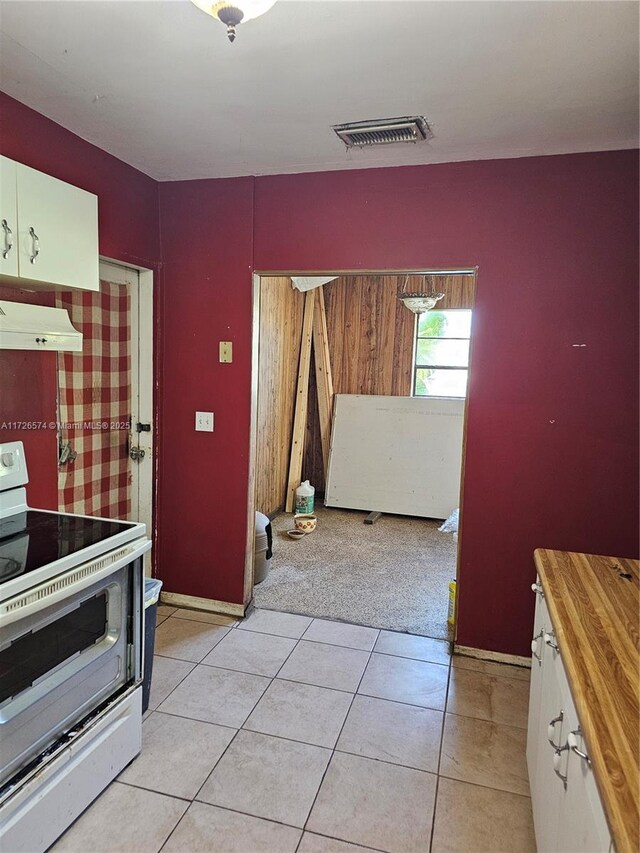 kitchen featuring electric stove, white cabinets, extractor fan, and light tile patterned floors