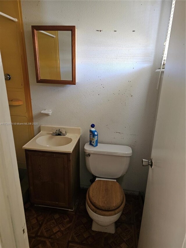 bathroom with vanity, parquet flooring, and toilet