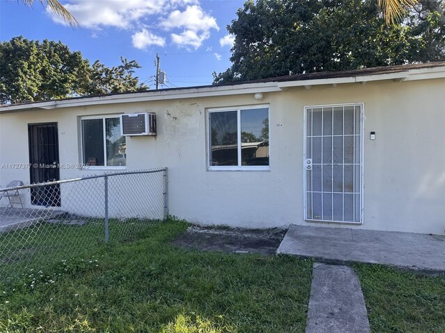 exterior space with a front lawn and a wall mounted air conditioner