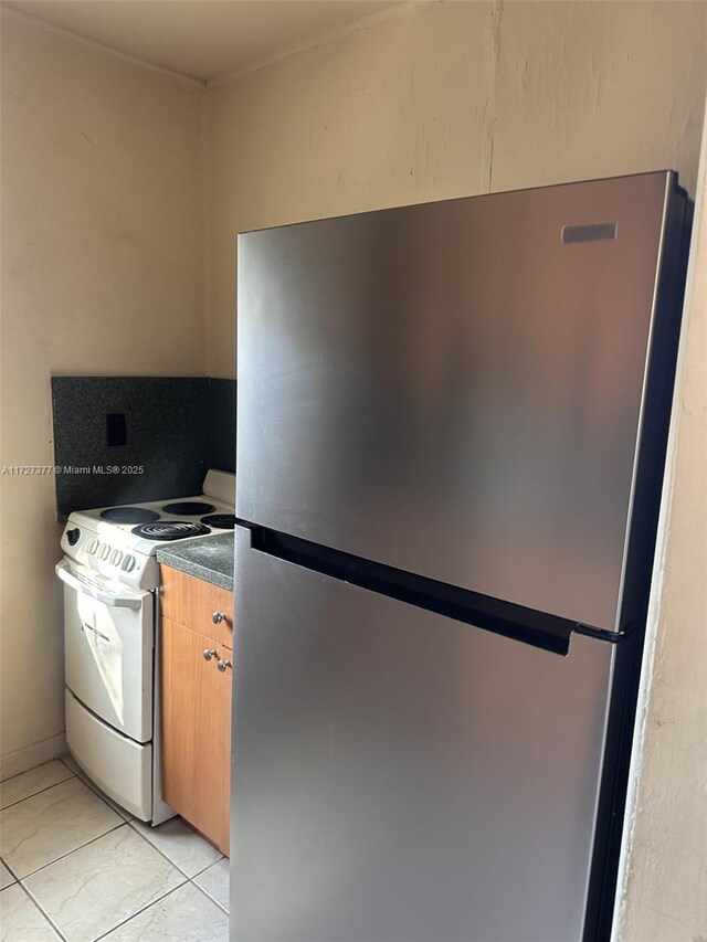 kitchen with stainless steel fridge, white electric range oven, and light tile patterned flooring