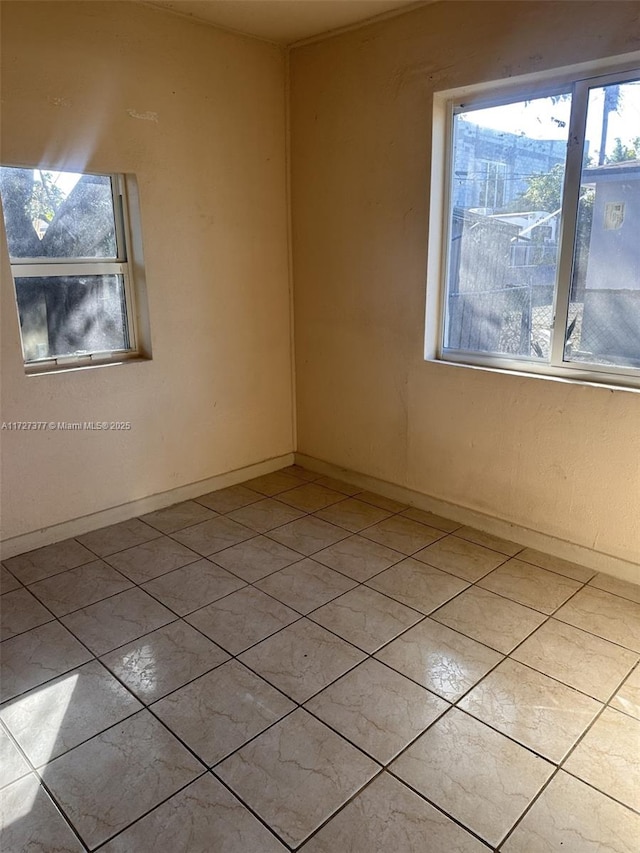 unfurnished room with baseboards and light tile patterned floors