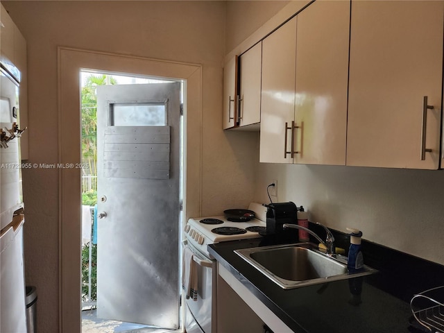 kitchen featuring electric stove, white cabinets, and sink