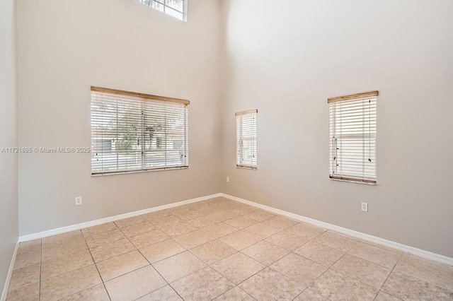 unfurnished room with a towering ceiling and light tile patterned floors