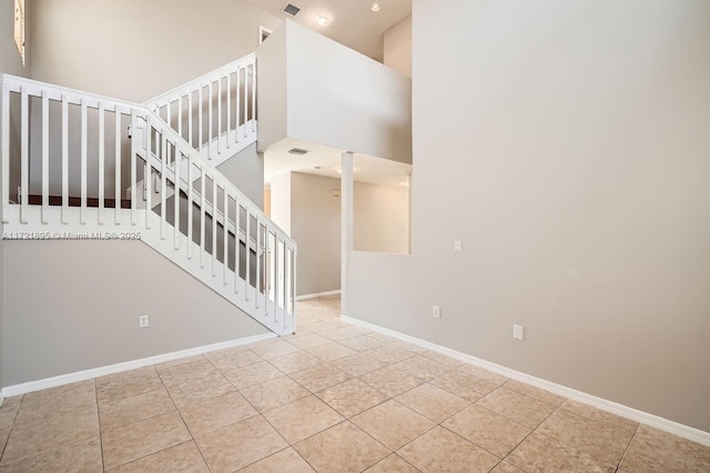 staircase featuring a high ceiling and tile patterned flooring