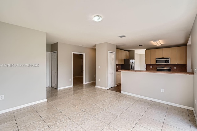 kitchen with light tile patterned floors, backsplash, appliances with stainless steel finishes, and kitchen peninsula