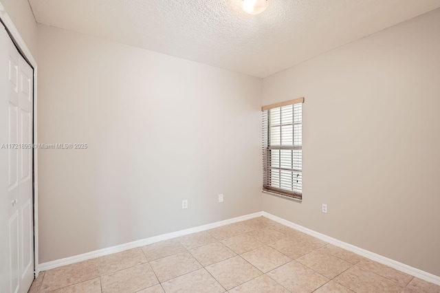 tiled empty room featuring a textured ceiling